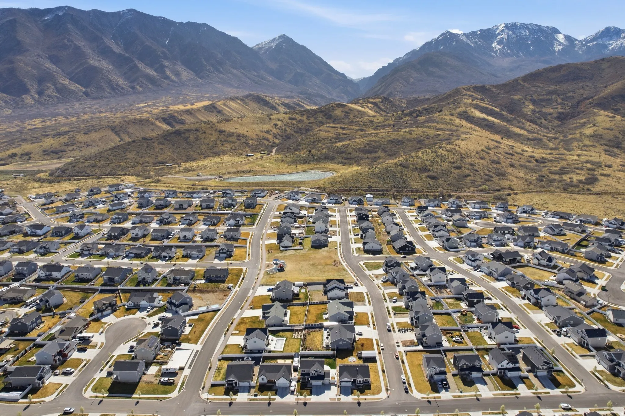 Aerial perspective of suburban area featuring a mountain backdrop and fishing pond