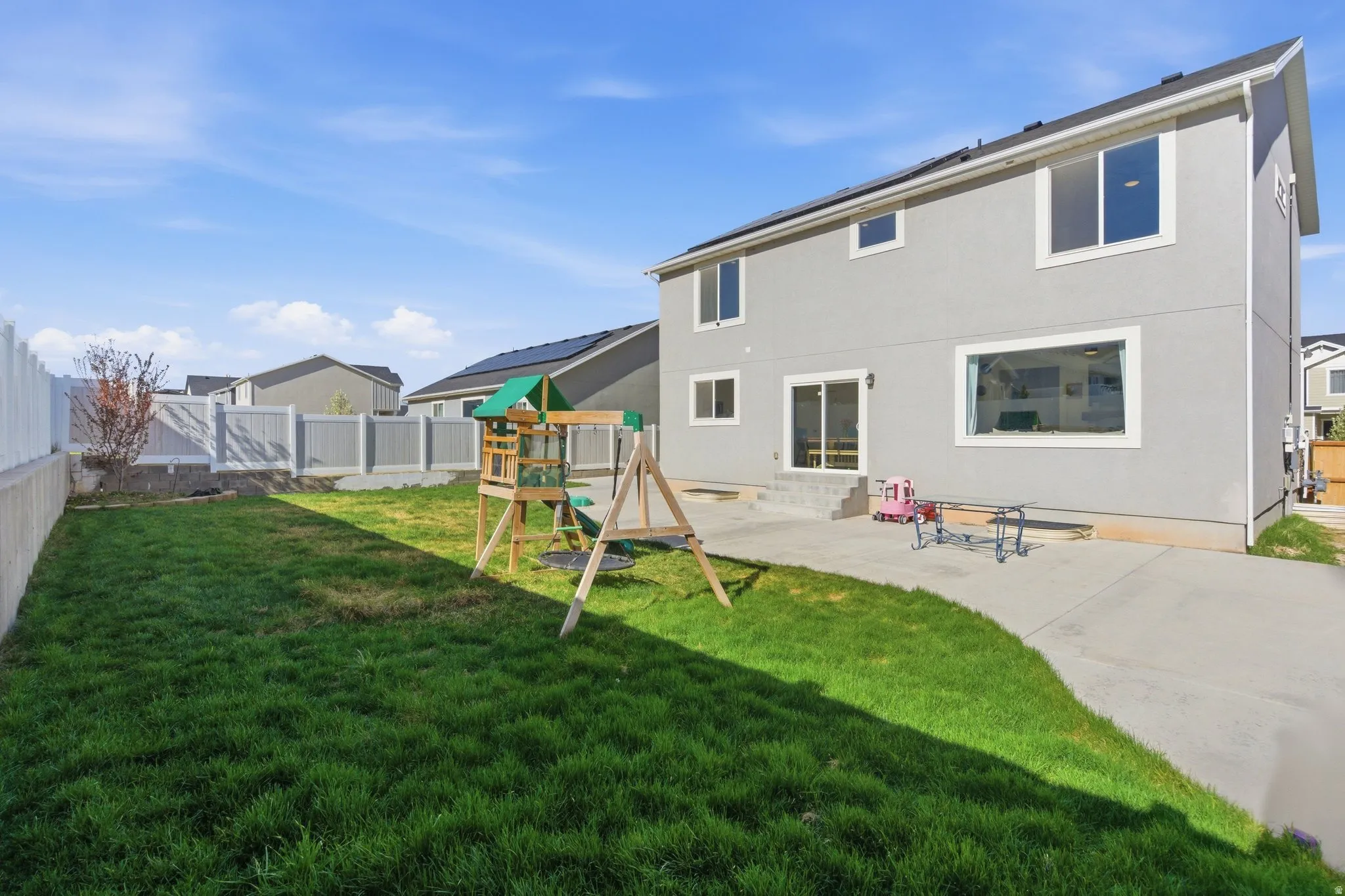 Back of property featuring a patio, a playground, a fenced backyard, and stucco siding