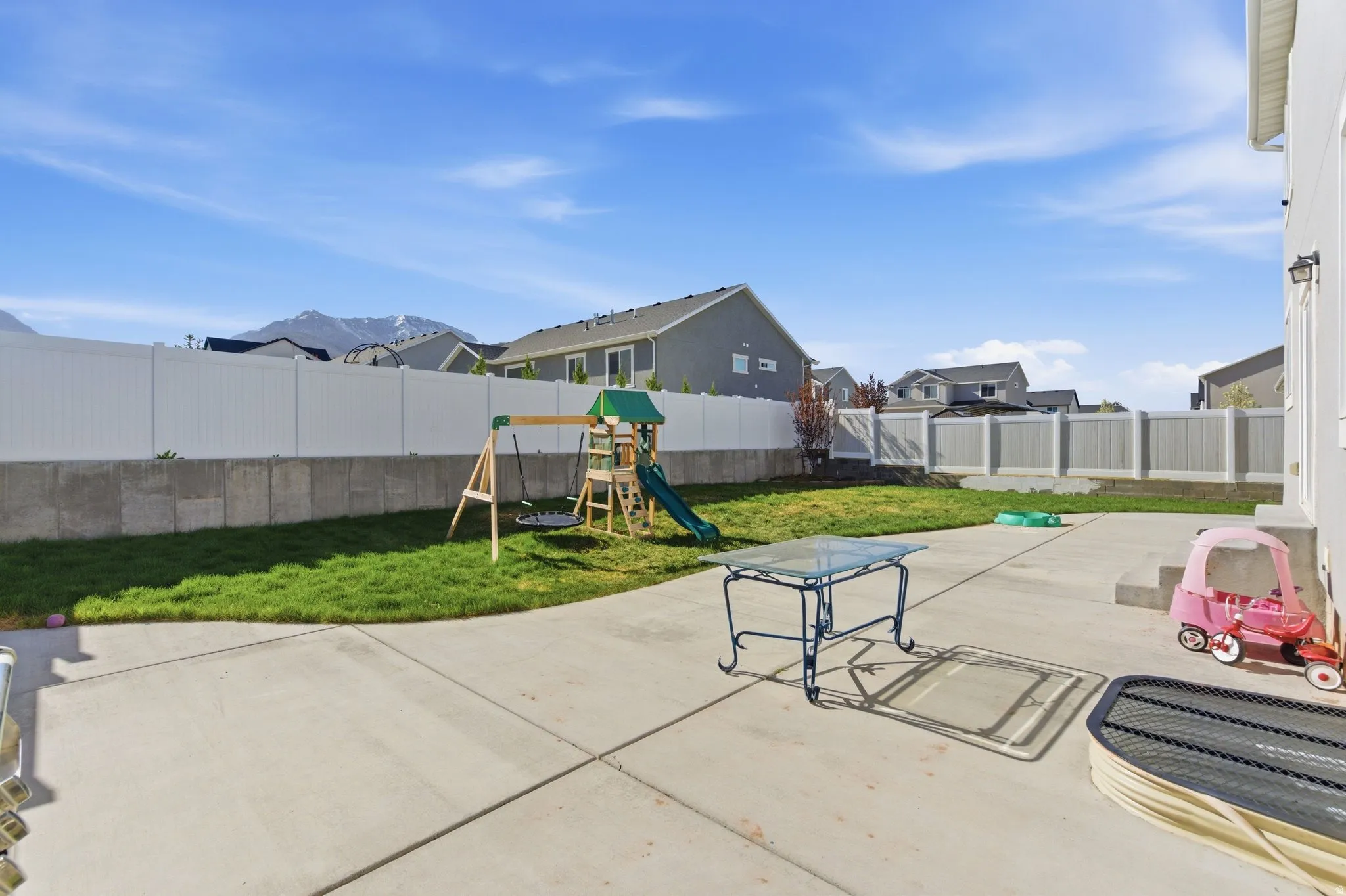 Fenced backyard featuring a playground, a patio, and a residential view