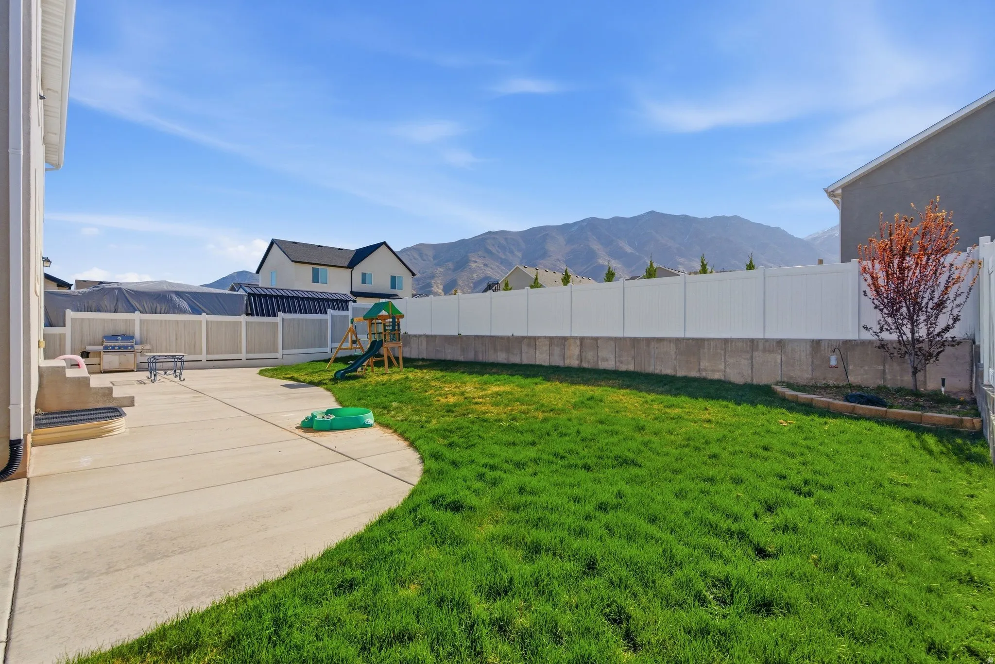 Fenced backyard with a mountain view, a playground, and a patio