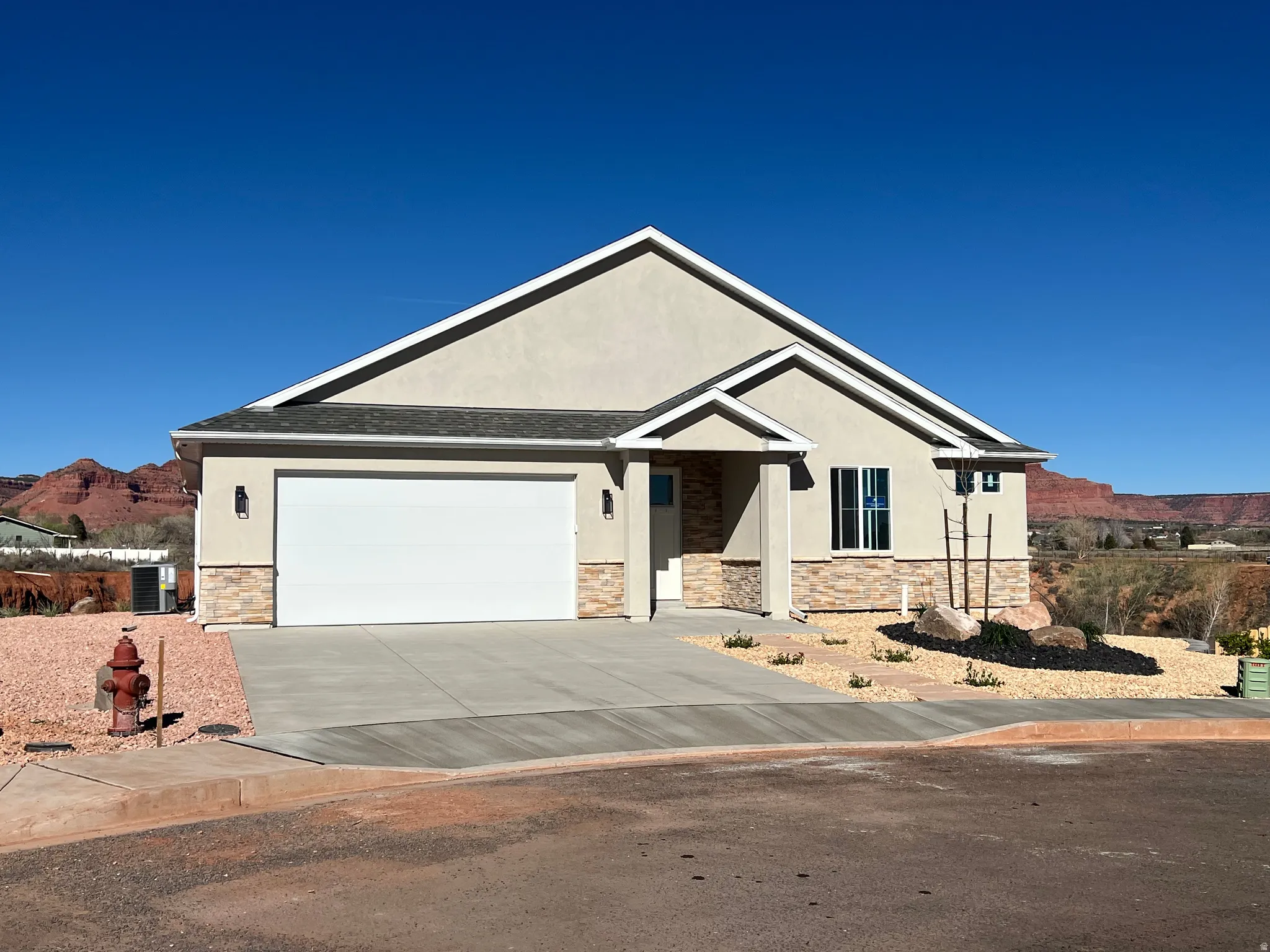 Single story home with stone siding, a mountain view, stucco siding, an attached garage, and concrete driveway