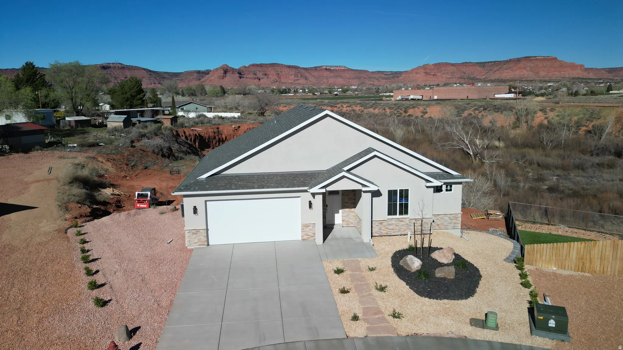 Single story home with an attached garage, concrete driveway, stone siding, and stucco siding