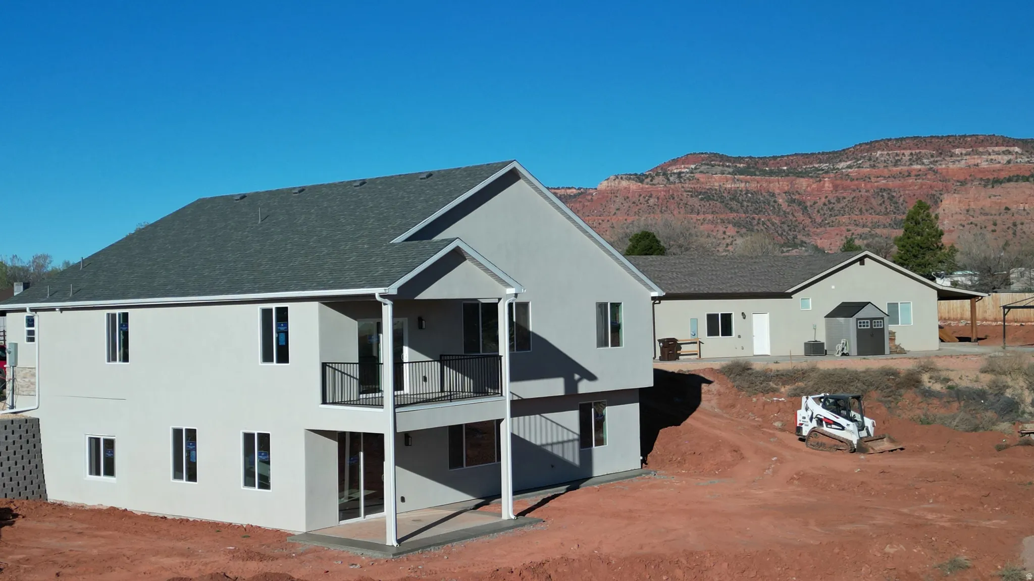 Back of property featuring a patio, stucco siding, a balcony, and a shingled roof