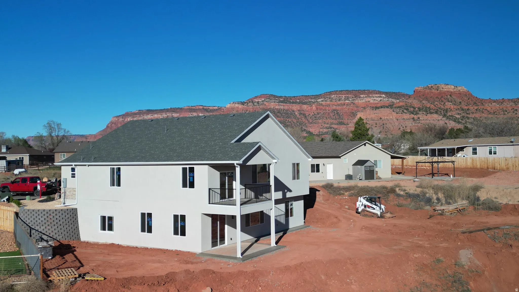 Back of property featuring a patio, a balcony, stucco siding, a mountain view, and a shingled roof