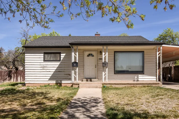 Bungalow-style home featuring a carport, a chimney, roof with shingles, and a porch