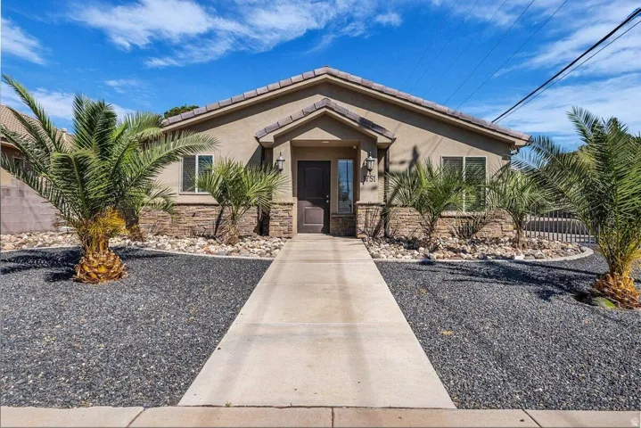 View of front of property featuring a tiled roof, stucco siding, and stone siding