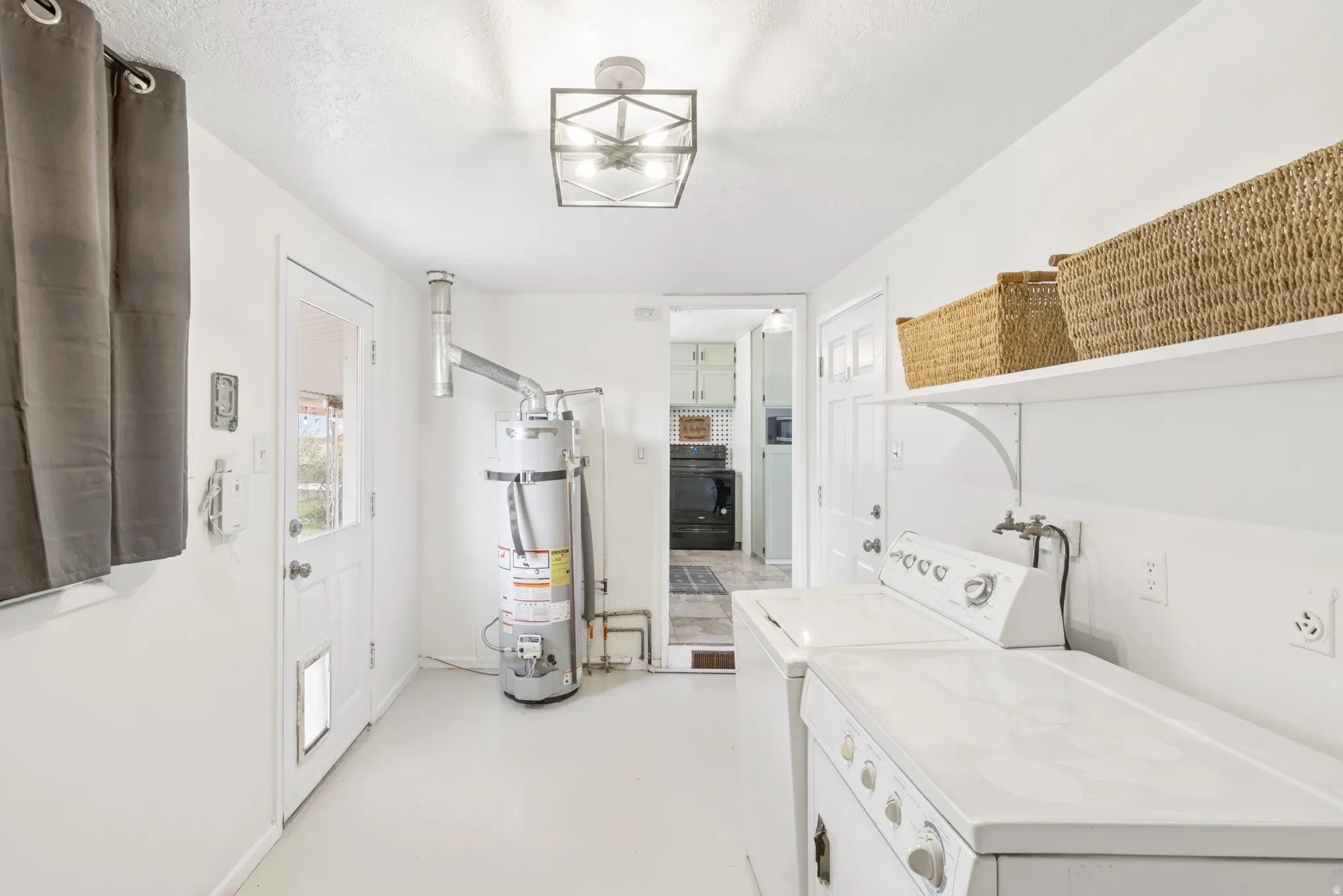 Laundry room featuring water heater, washer and clothes dryer, and finished concrete flooring