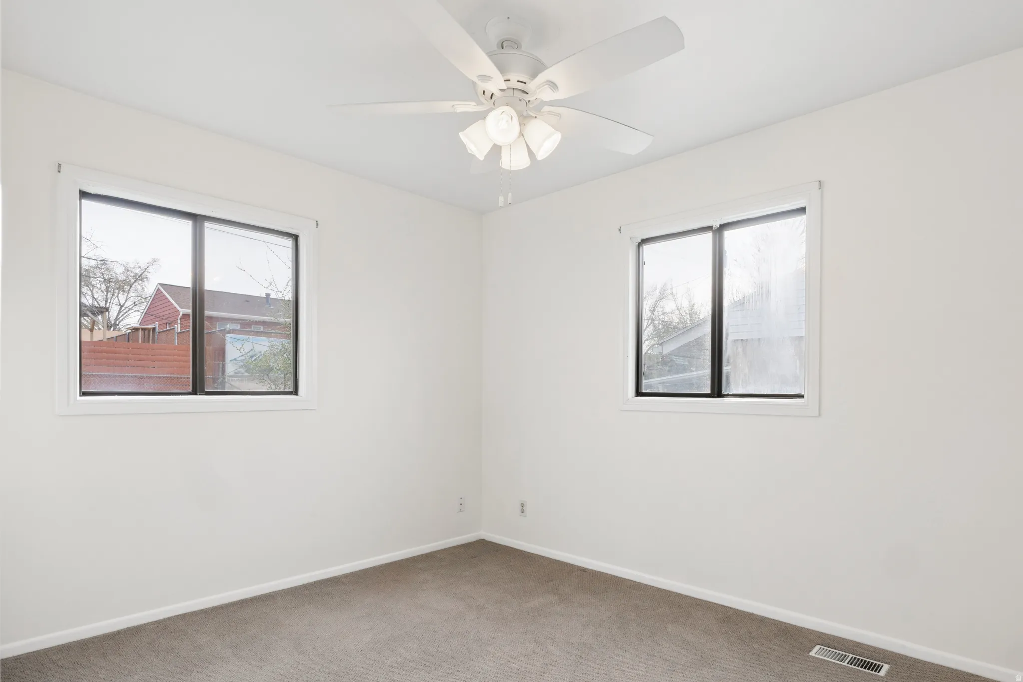 Carpeted spare room featuring plenty of natural light and a ceiling fan