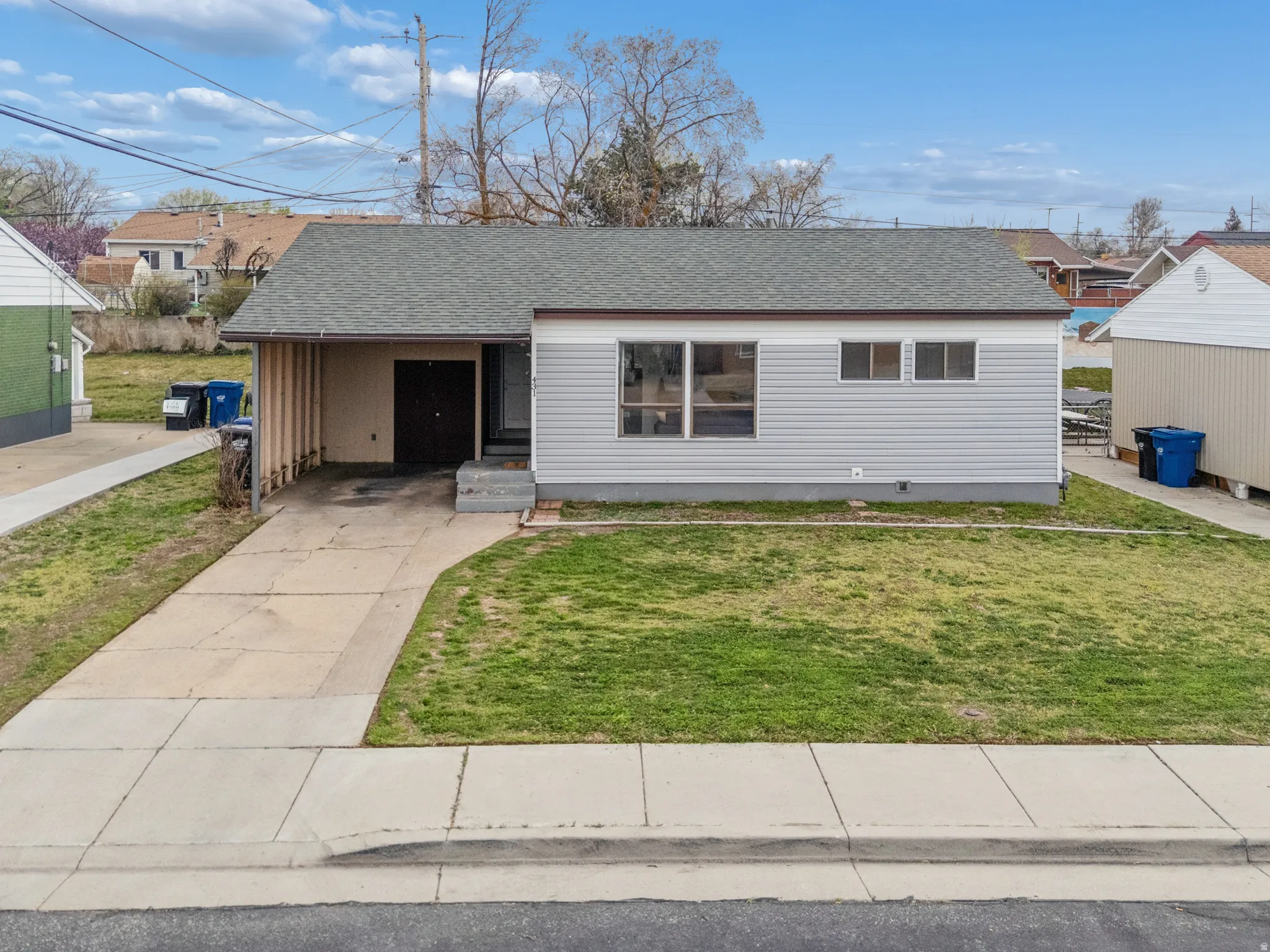 View of front of house featuring roof with shingles, a front lawn, a carport, and driveway