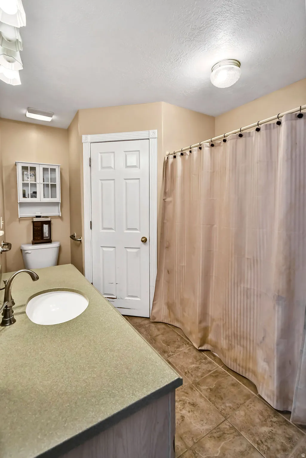 Full bath with vanity, a shower with curtain, and a textured ceiling