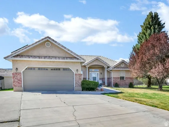 Ranch-style home with brick siding, concrete driveway, a garage, and stucco siding