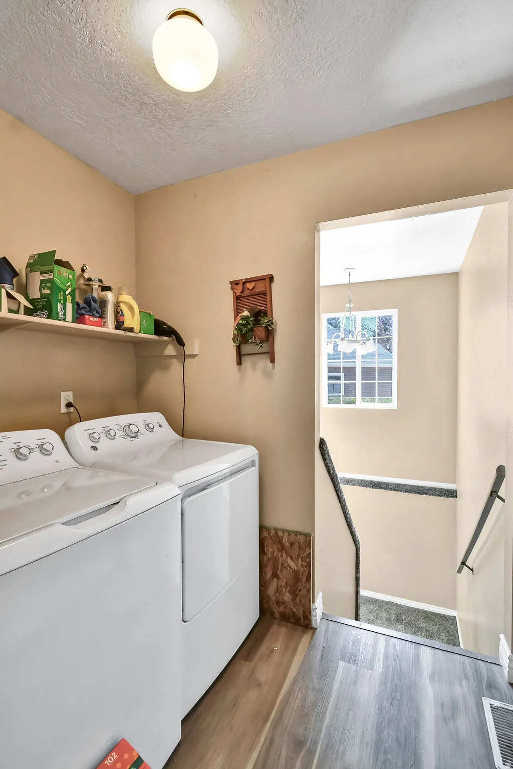 Laundry area with washer and dryer, wood finished floors, and a textured ceiling
