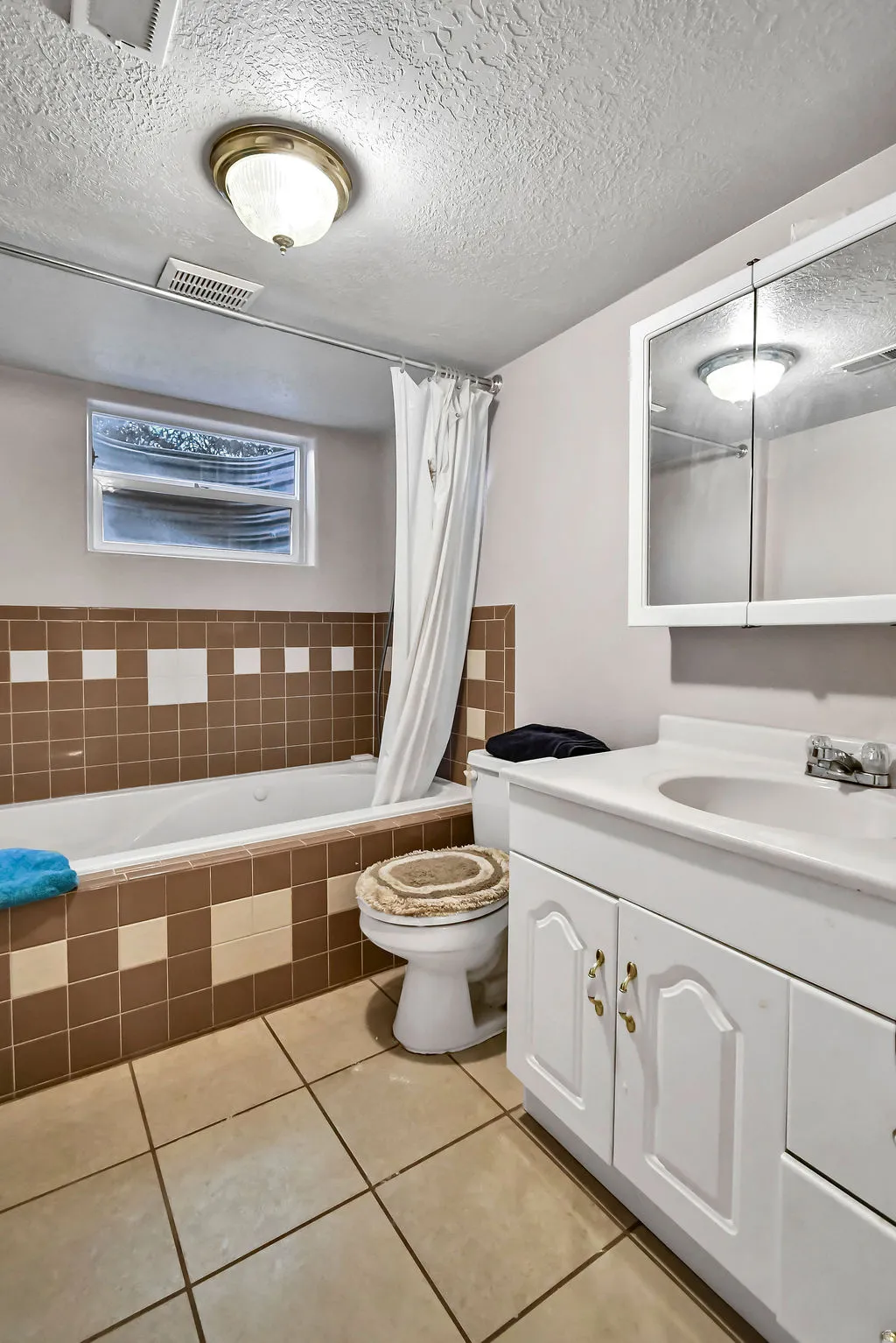 Full bathroom with vanity, a textured ceiling, light tile patterned floors, and tiled shower / bath combo