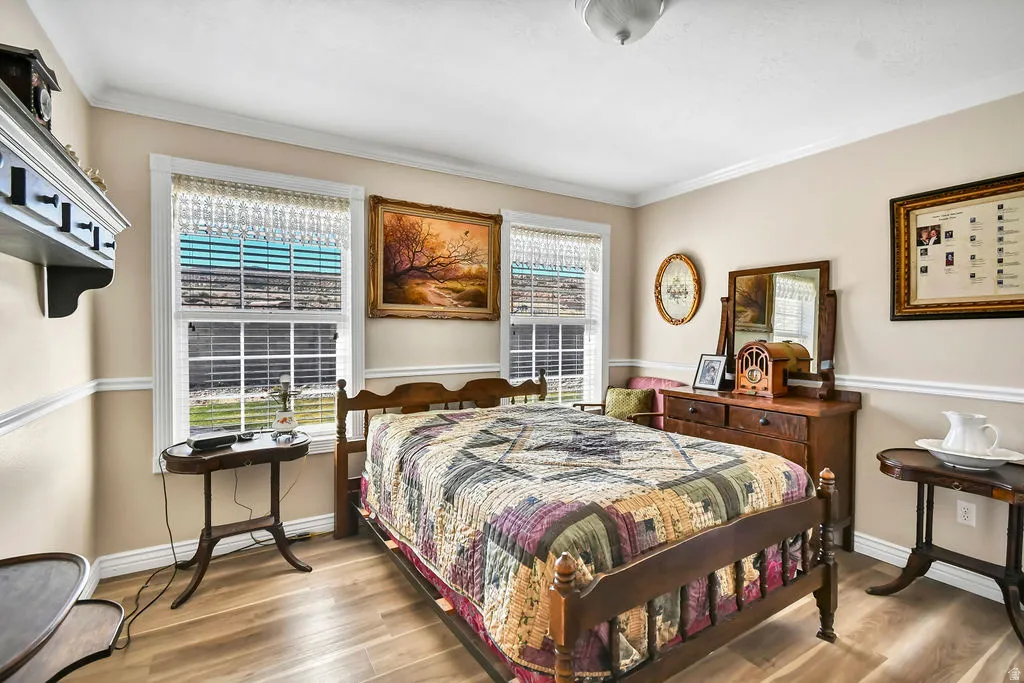 Bedroom with wood finished floors and crown molding