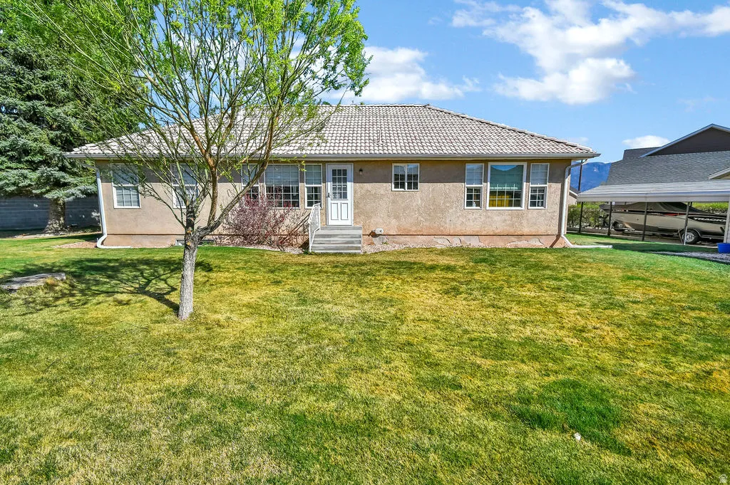 Back of property featuring a yard, stucco siding, and a tile roof