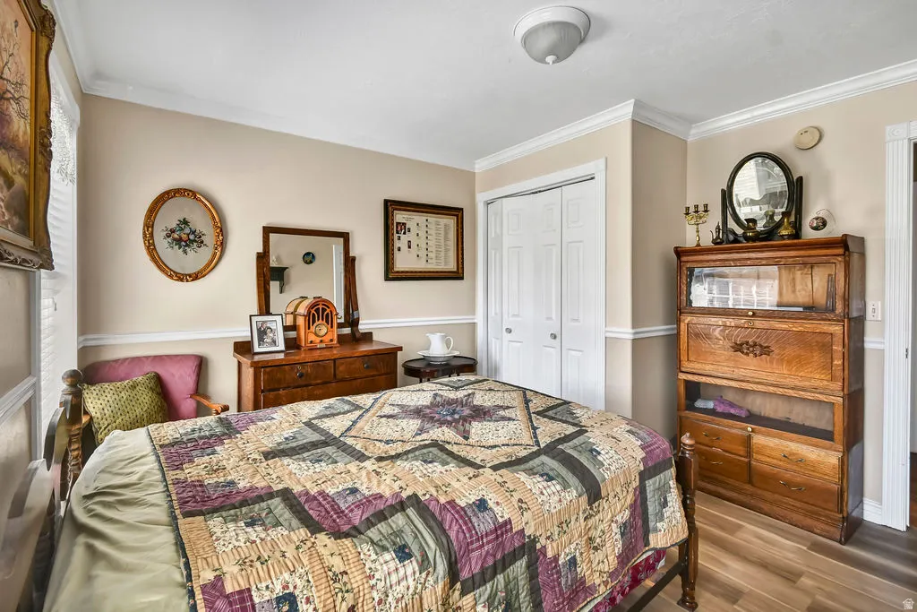 Bedroom featuring a closet, ornamental molding, and wood finished floors