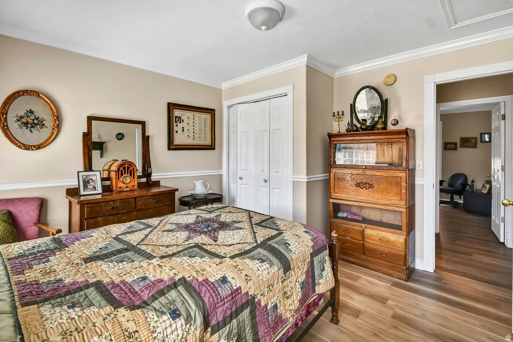 Bedroom featuring crown molding, wood finished floors, and a closet