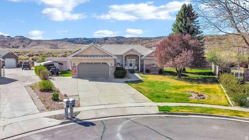 View of front of house with a front lawn, a mountain view, brick siding, driveway, and an attached garage