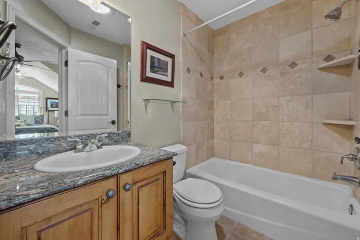Ensuite bathroom with vanity, shower / tub combination, a ceiling fan, and light tile patterned floors
