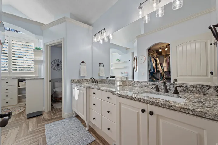 Bathroom with double vanity, a walk in closet, and parquet flooring