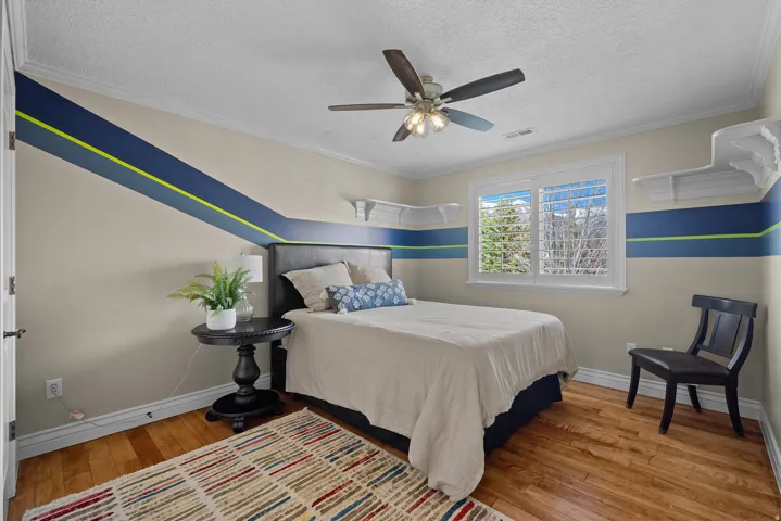 Bedroom featuring light wood-style flooring, ceiling fan, ornamental molding, and a textured ceiling