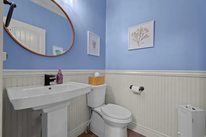 Half bath featuring wainscoting and wood finished floors