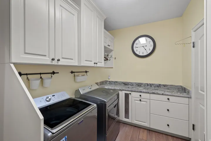 Laundry area with cabinet space, dark wood-style flooring, and separate washer and dryer