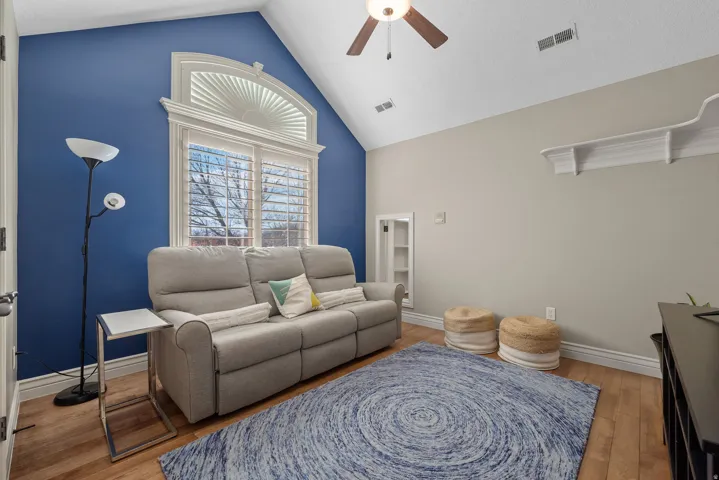 Living area featuring a ceiling fan, light wood-style flooring, and a high ceiling