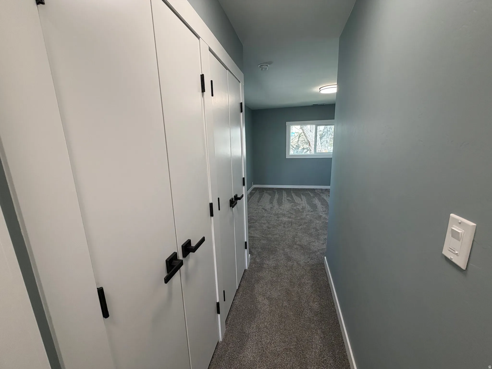 Hall with dark colored carpet and baseboards