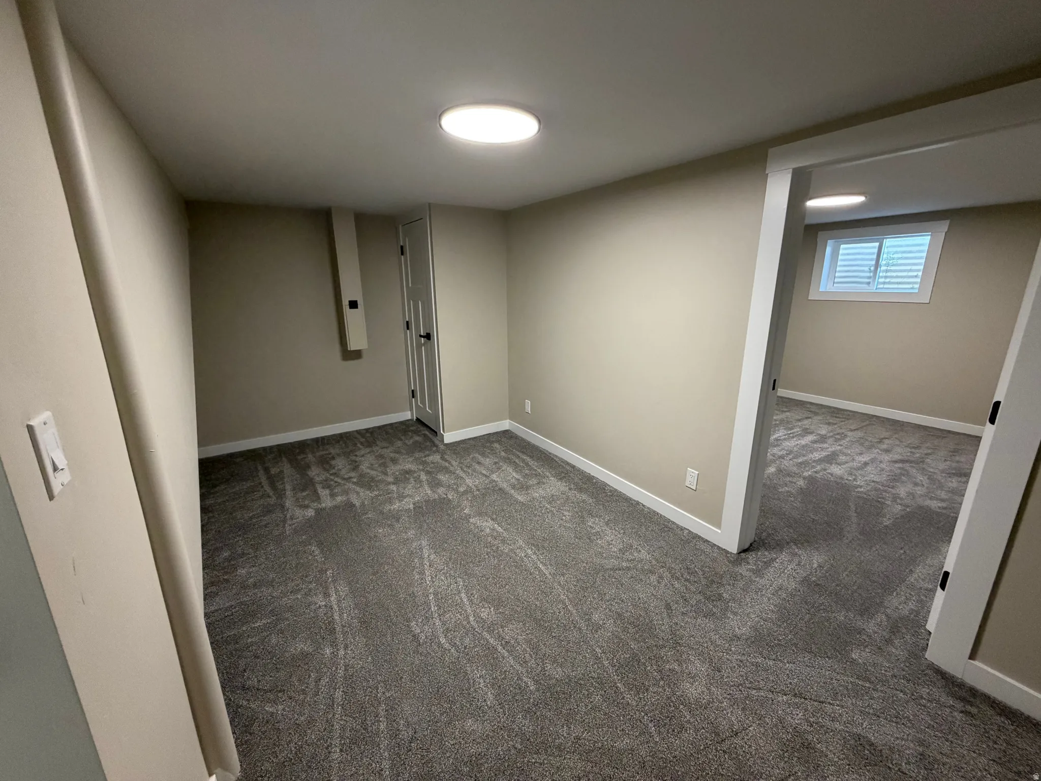 Basement with dark carpet and baseboards