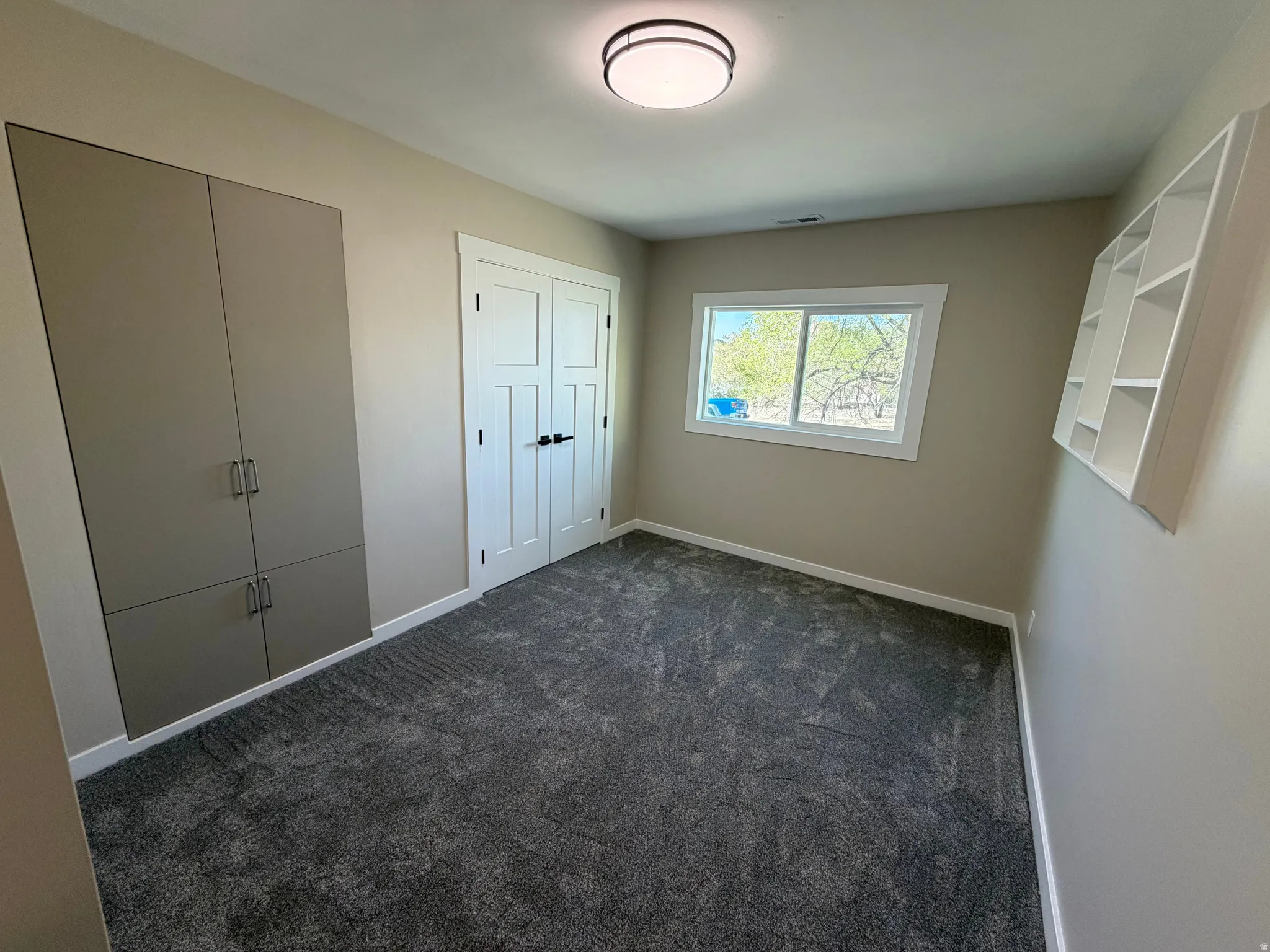 Unfurnished bedroom featuring dark colored carpet and two closets