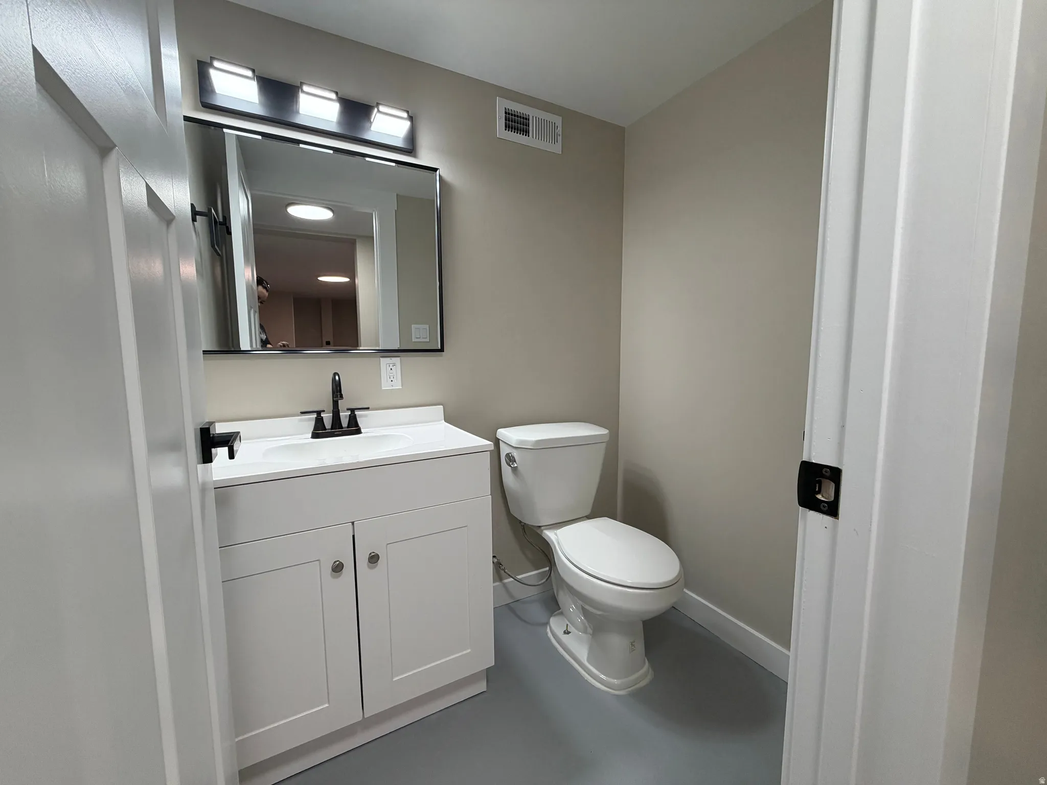 Half bath with vanity and finished concrete flooring