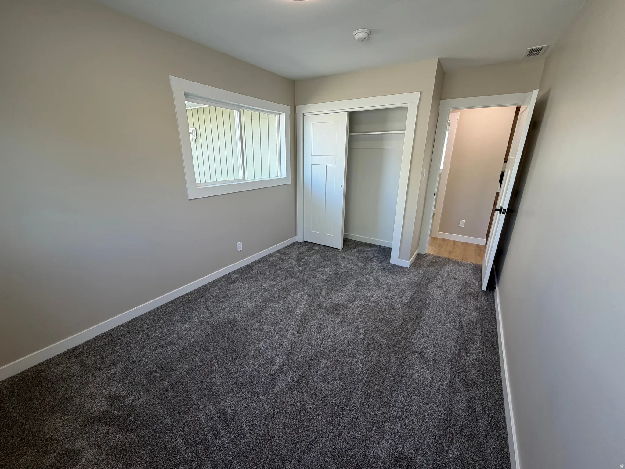 Unfurnished bedroom featuring dark colored carpet and a closet
