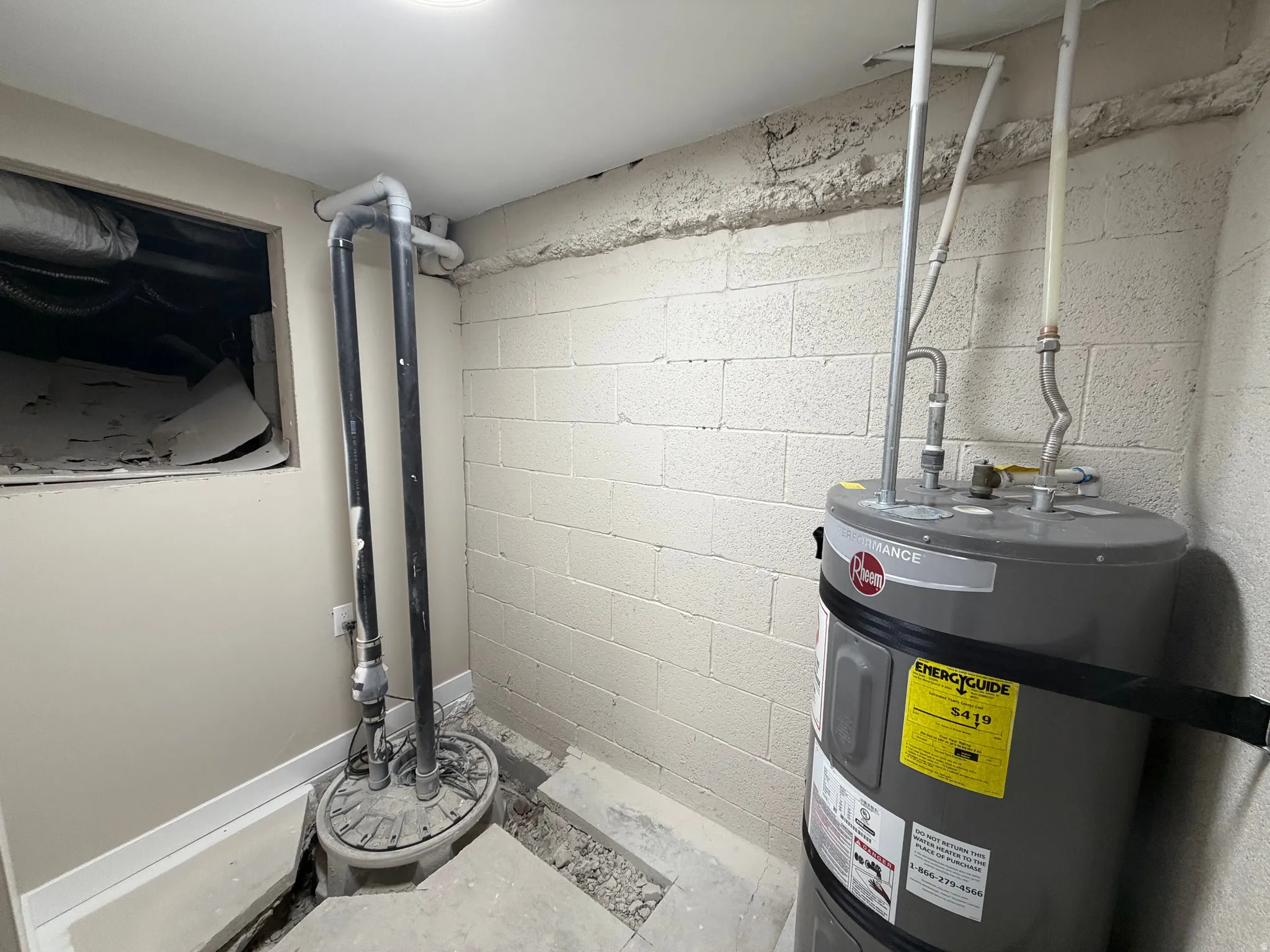 Utility room featuring strapped water heater and drainage system