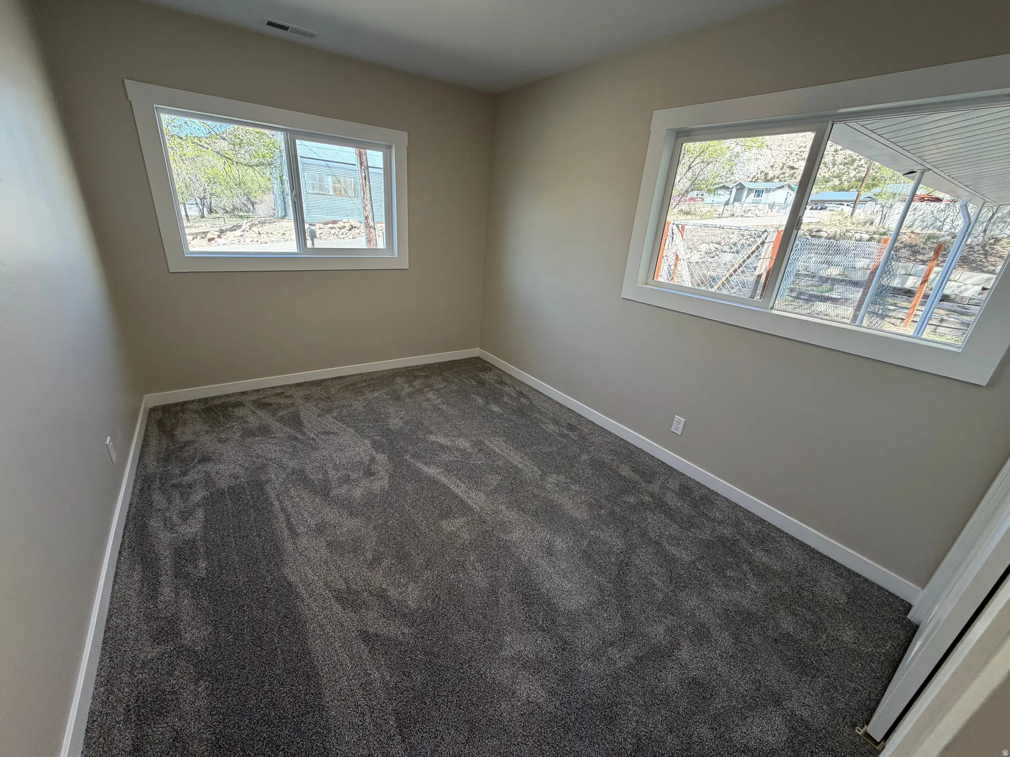 Empty room featuring dark carpet and baseboards