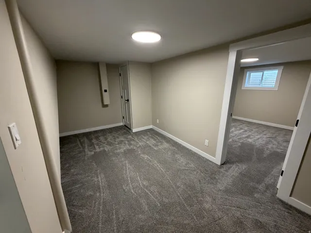 Basement with dark carpet and baseboards