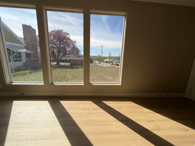 Unfurnished room with healthy amount of natural light, a residential view, and wood finished floors