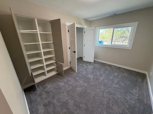 Unfurnished bedroom featuring dark colored carpet and a closet
