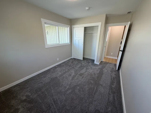 Unfurnished bedroom featuring dark colored carpet and a closet