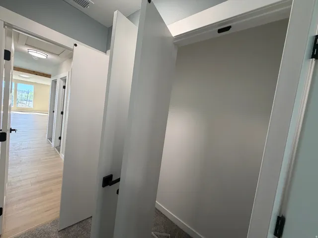 Corridor featuring baseboards and dark carpet