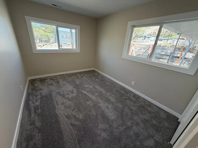 Empty room featuring dark carpet and baseboards