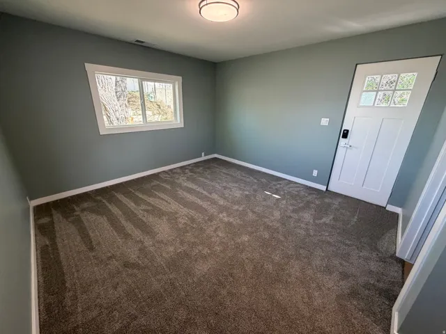 Empty room featuring dark colored carpet and baseboards