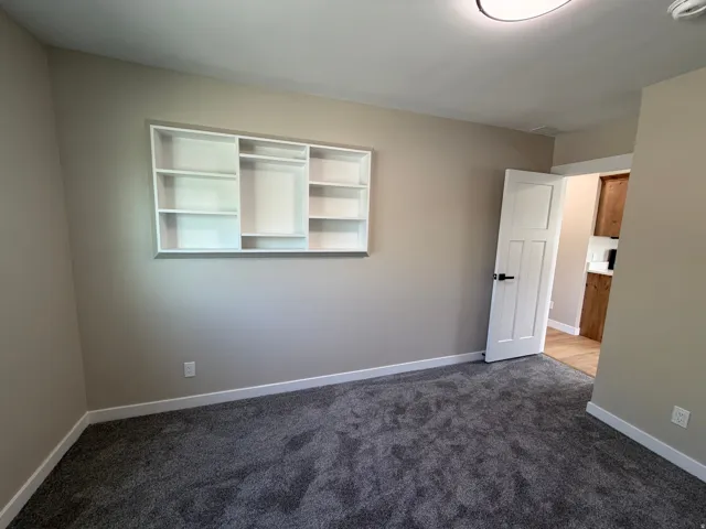Spare room with dark carpet and baseboards