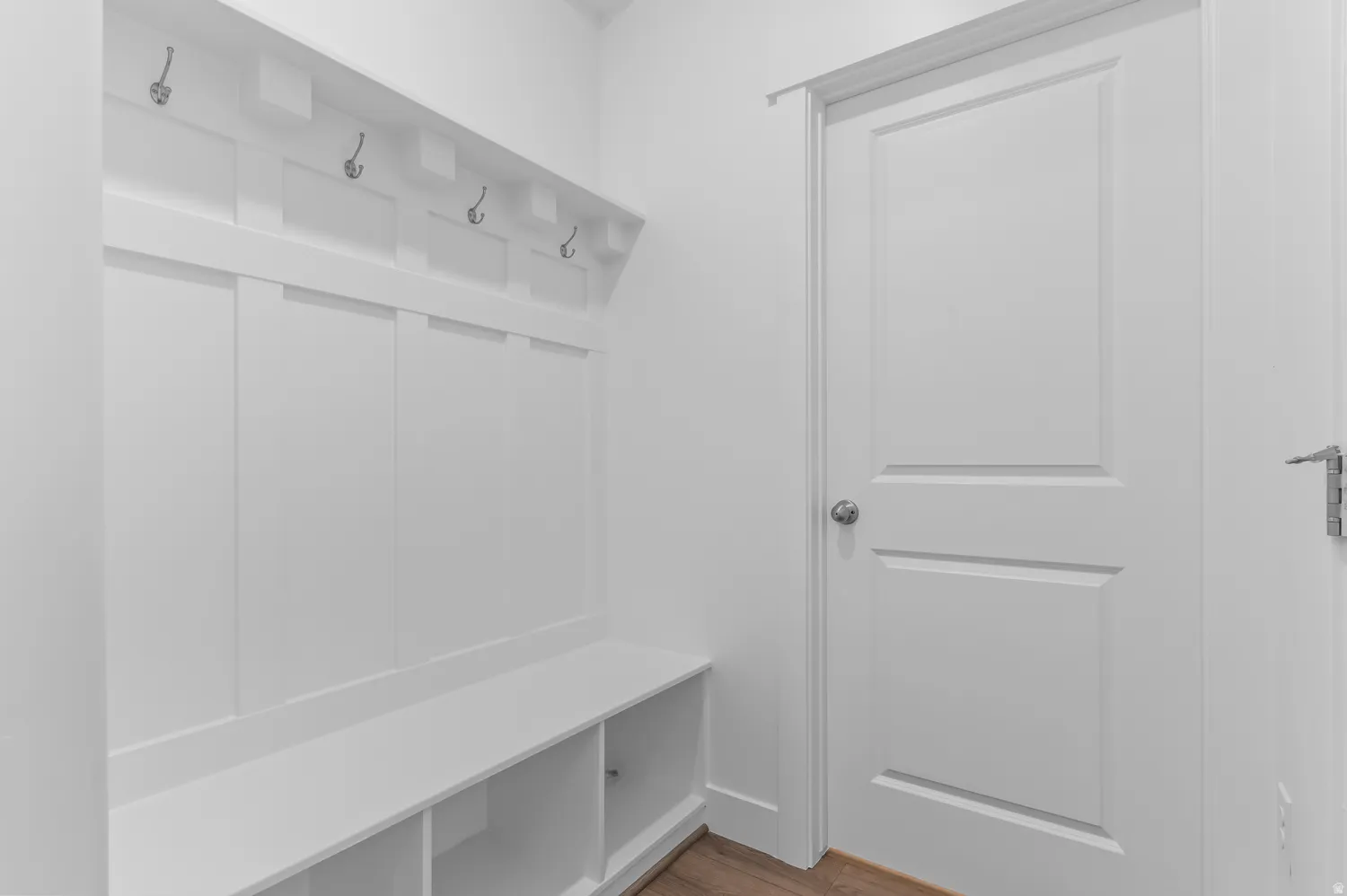 Built-in mudroom bench with storage cubbies, wall-mounted coat hooks, and classic paneling