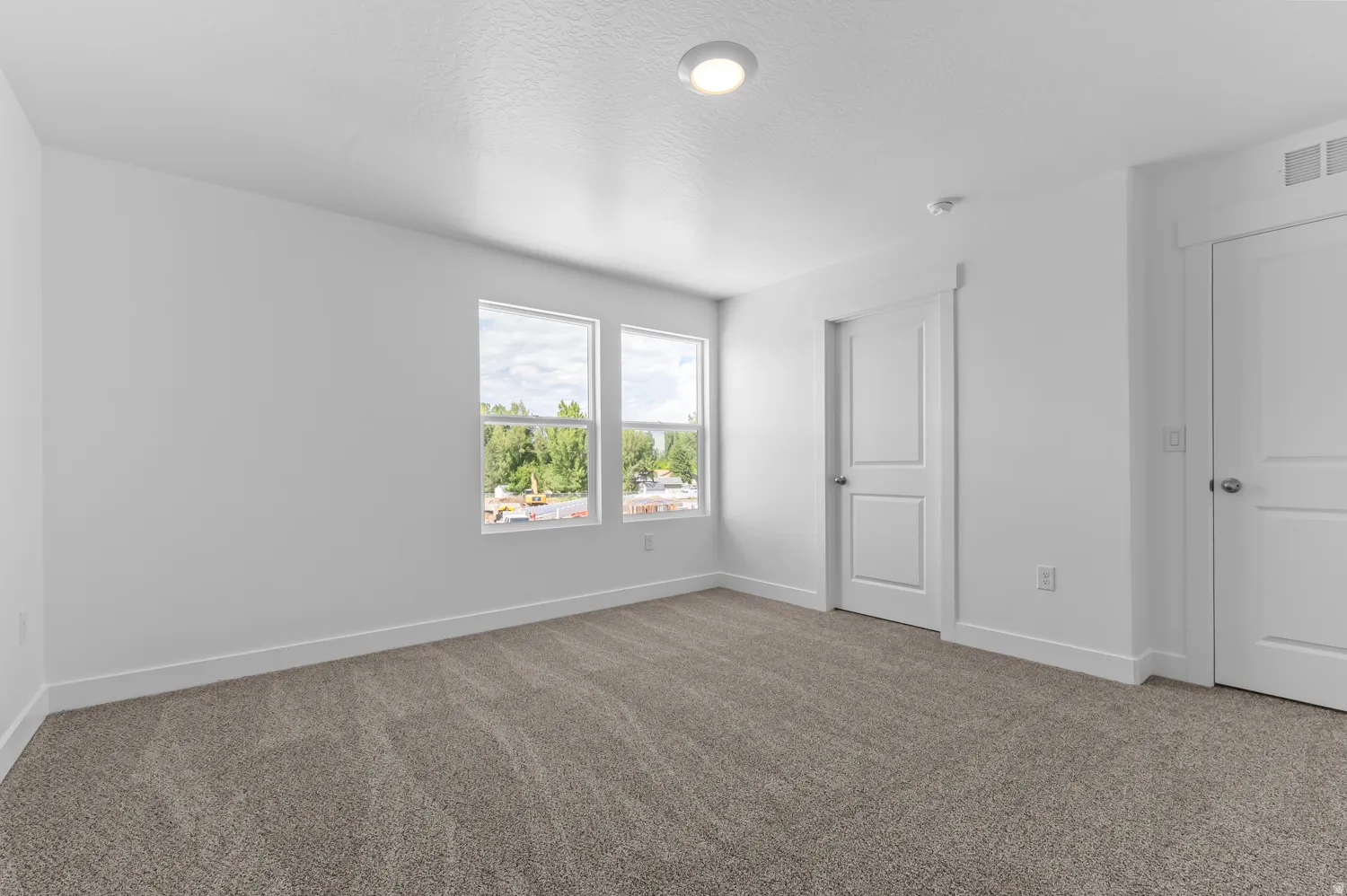 Two panel doors, two windows, recessed lighting, and neutral carpeting