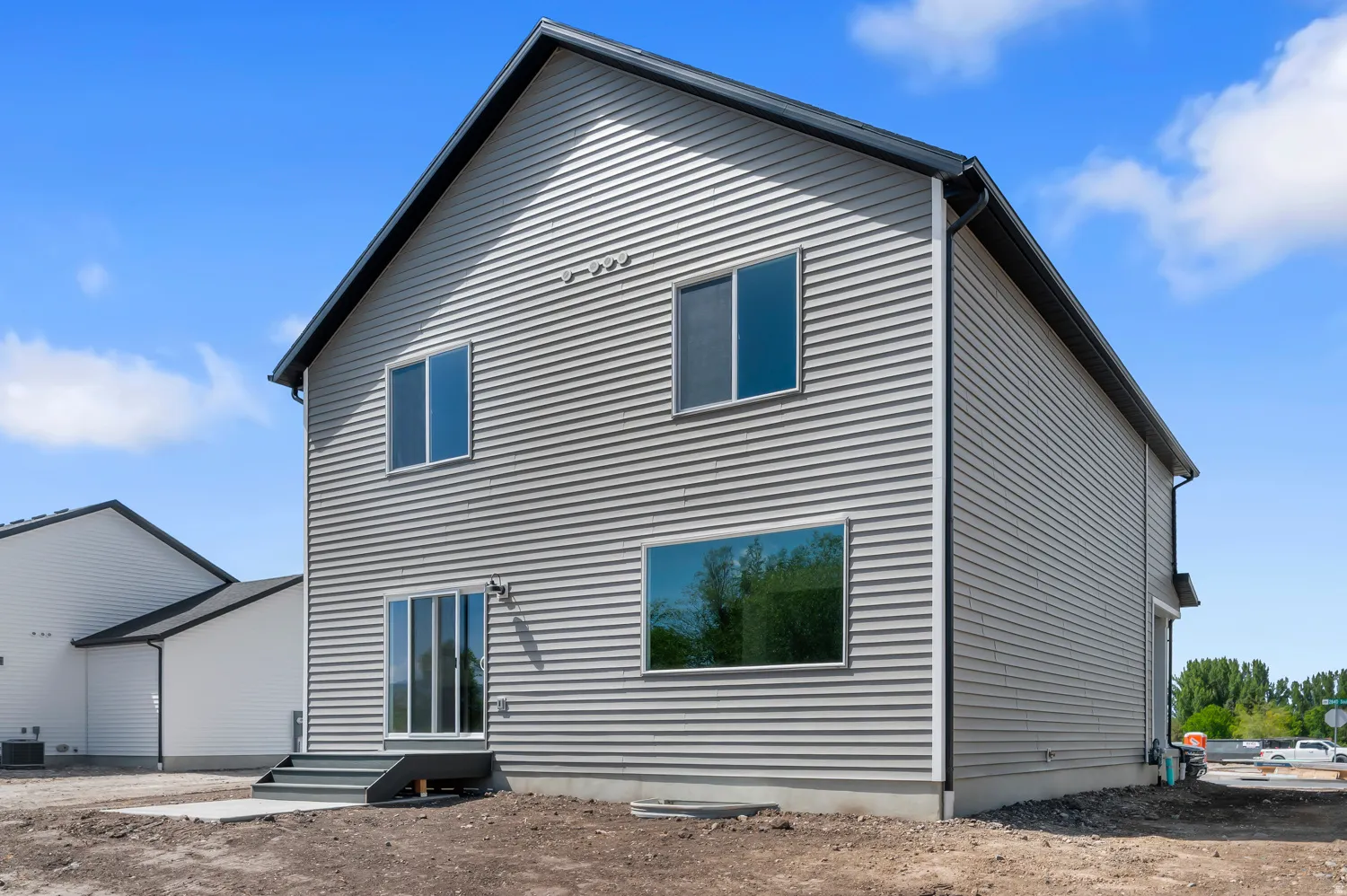 Contemporary two-story exterior with horizontal siding, dark roof, dark gutters, multiple windows, and a sliding glass door
