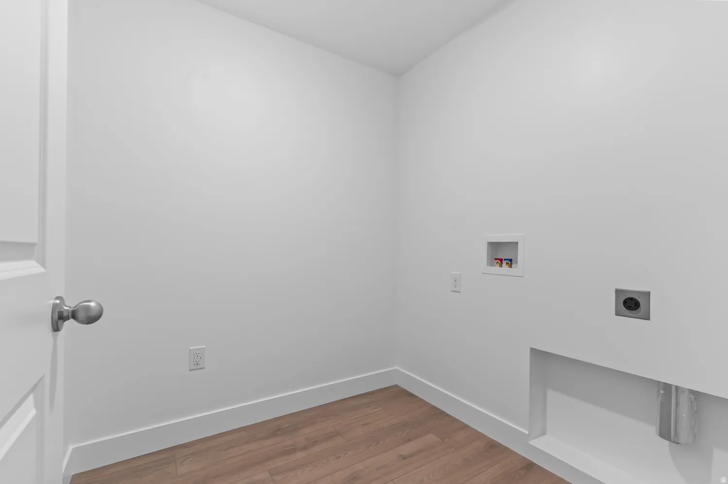 Dedicated laundry utility space featuring white walls, wood-finish flooring, and essential hookups