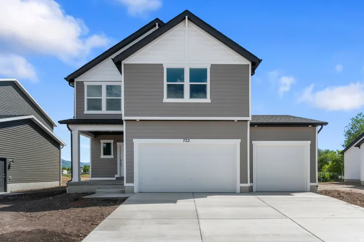 Contemporary exterior with gray siding and white trim, featuring a two-car garage, an additional single-car garage, and a covered entry porch