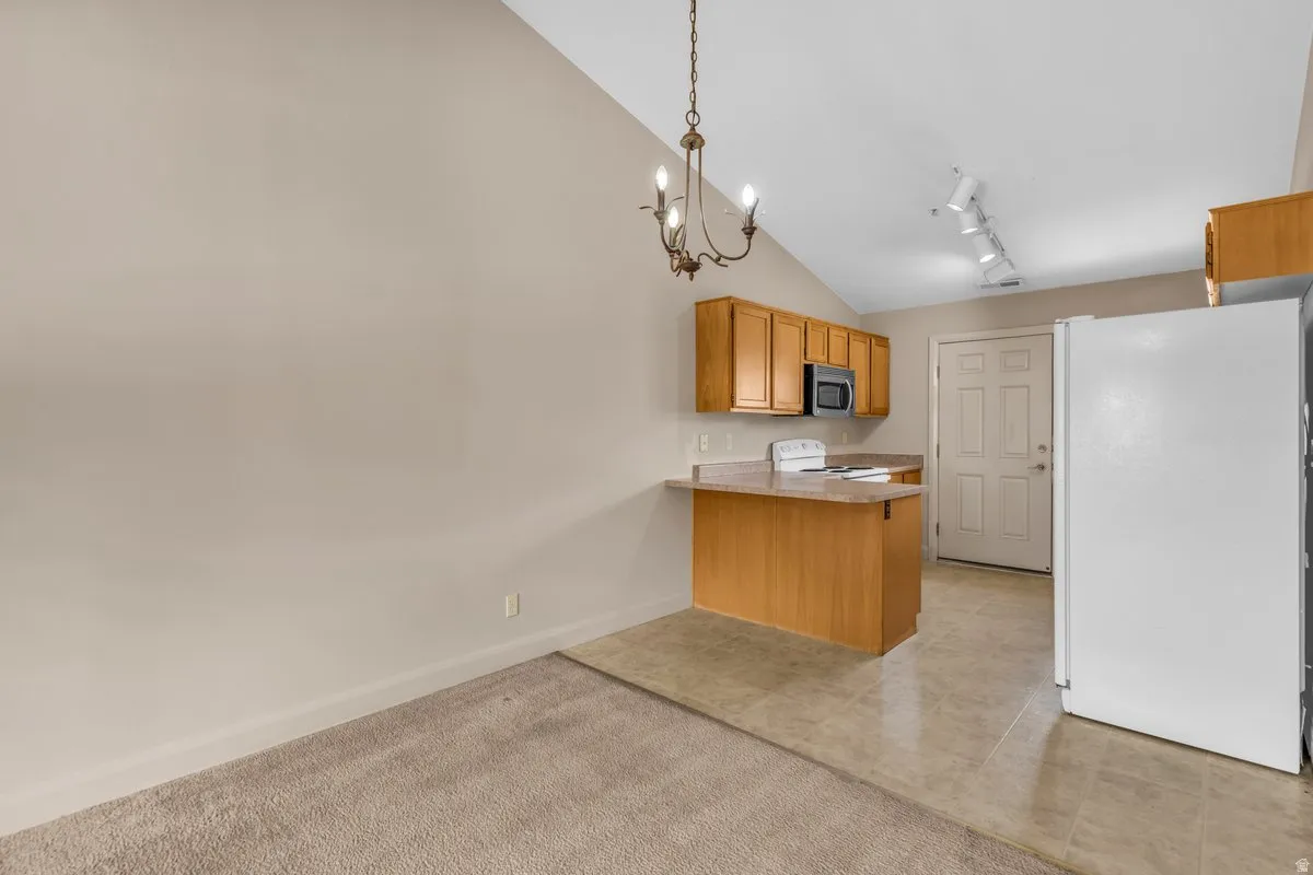 Kitchen area featuring wood-finish cabinetry, a breakfast bar, recessed microwave, and a white refrigerator