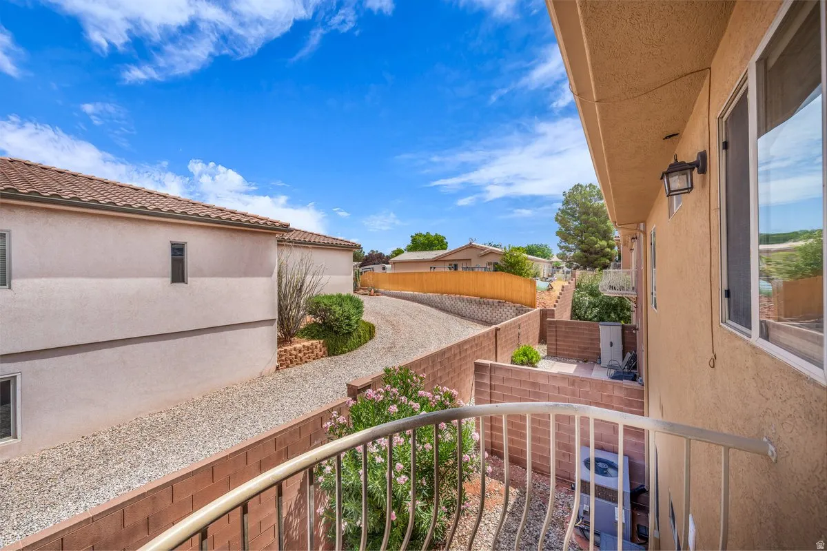 Exterior stucco finish featuring multiple windows, a tiled roof, and a gravel driveway